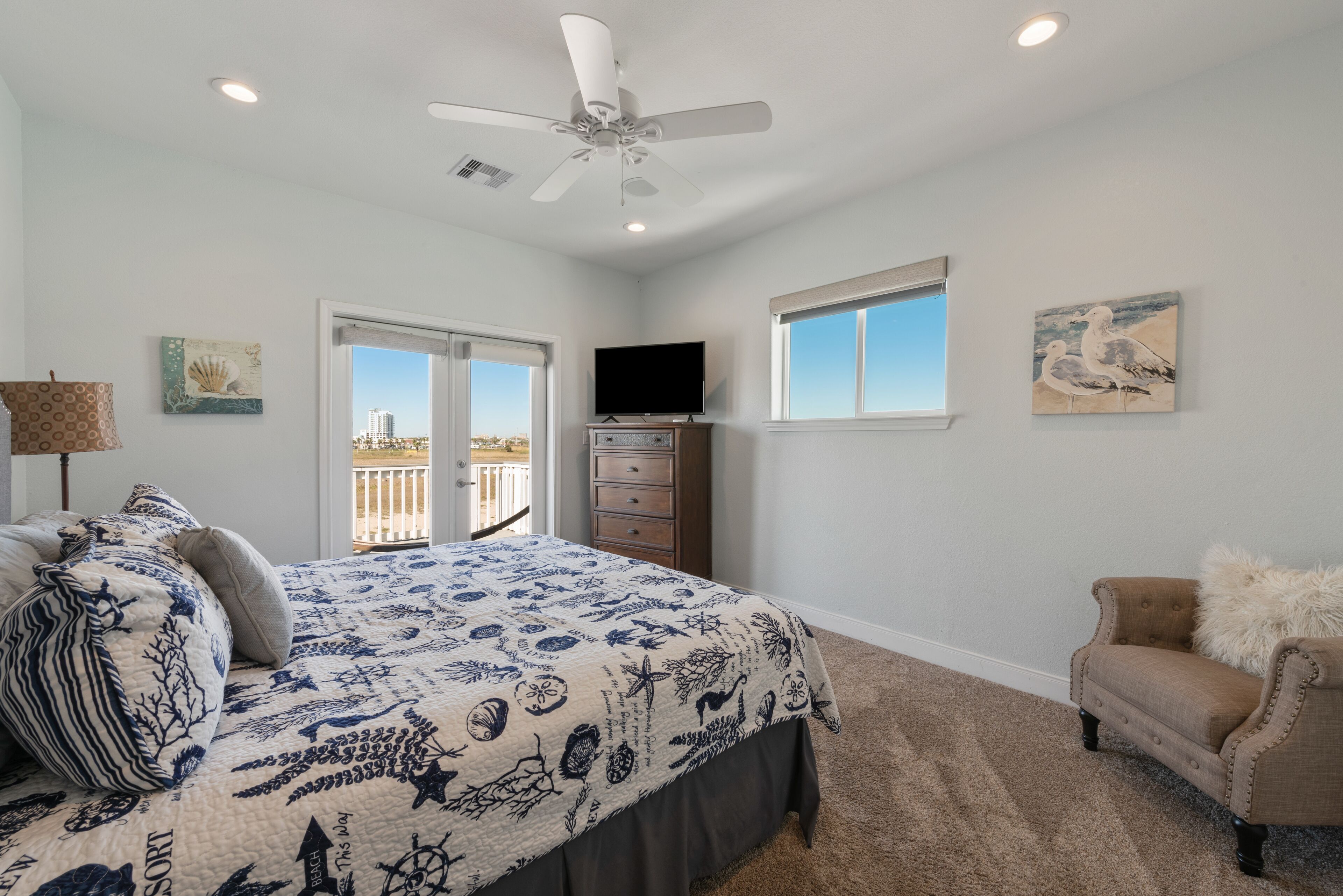 A bedroom with a bed, a ceiling fan, a TV, and a window.