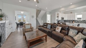 A spacious living room with a leather sofa, a coffee table, and a dining area with chairs. - Family Friendly Beach House in Gated Beach Resort (Galveston)