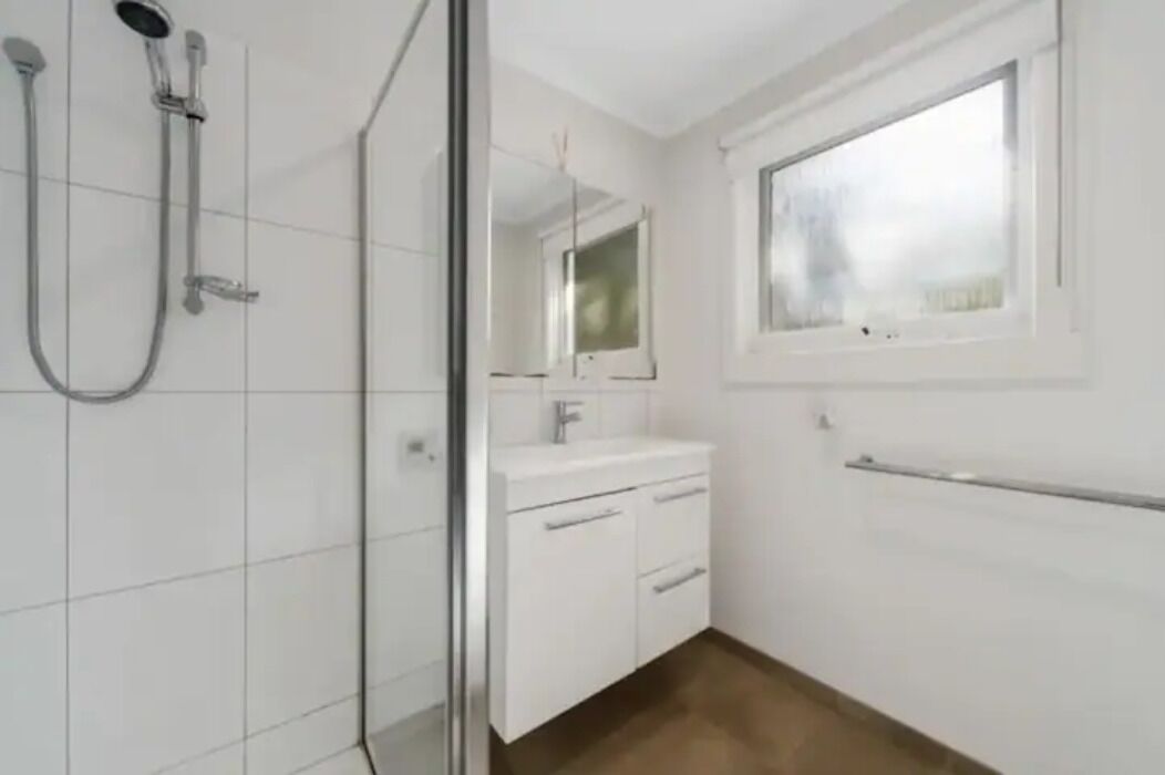 A bathroom with a glass shower enclosure, a white sink, and a mirror above it.