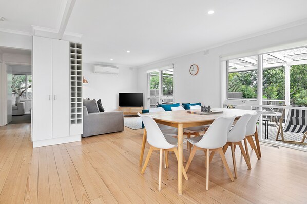 A modern living room with a dining area, large windows, and a built-in TV.