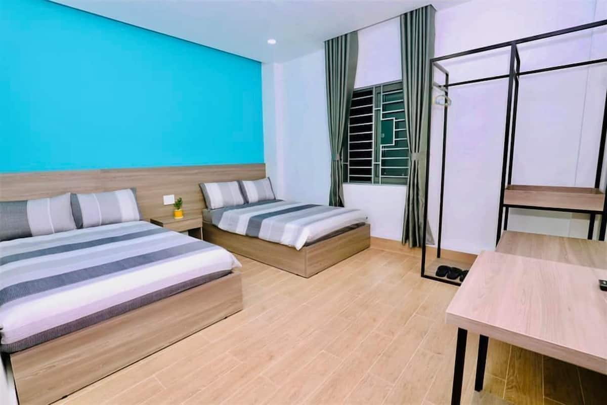Una habitación con dos camas, una mesa y una ventana con cortinas.