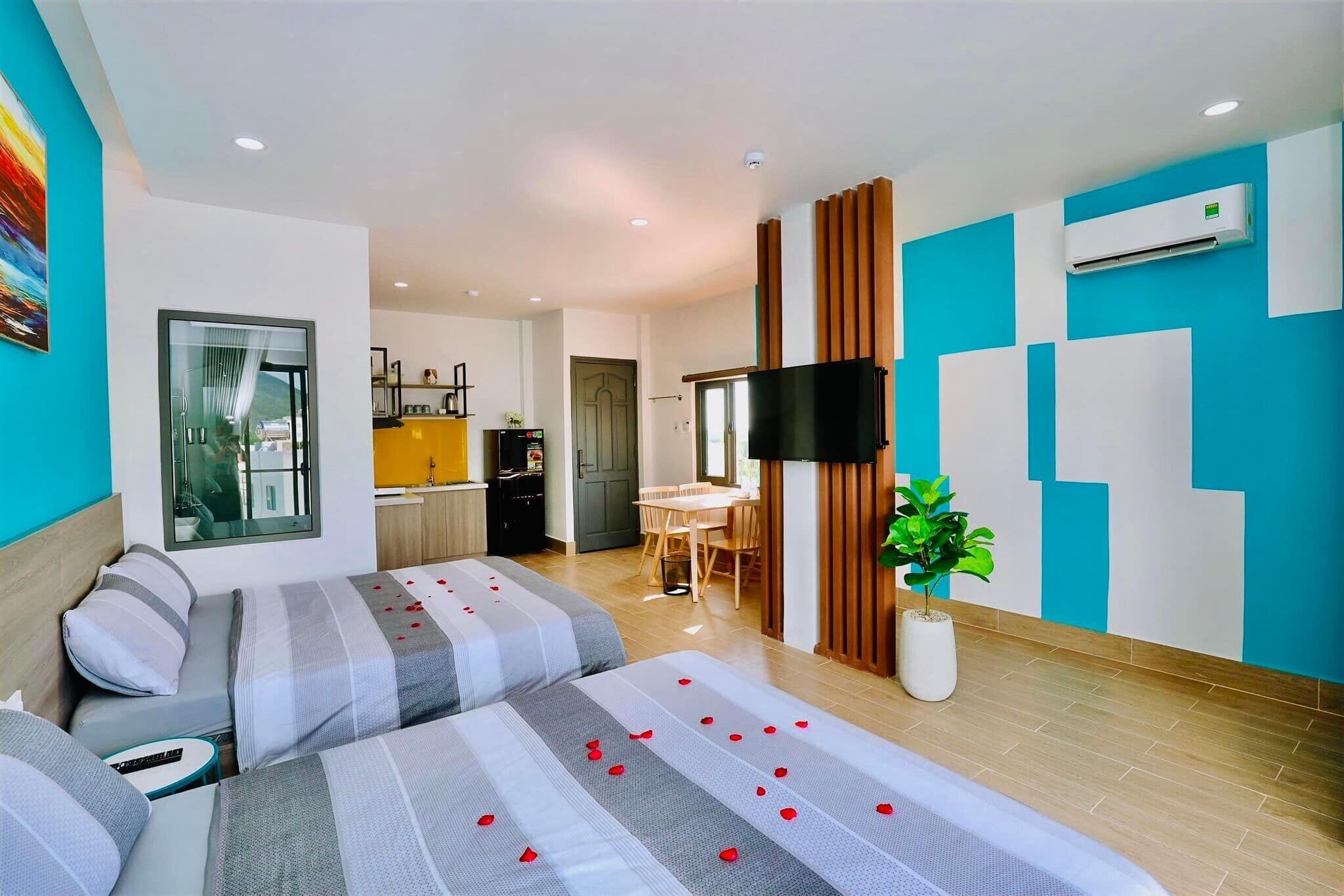 Habitación de hotel con dos camas, televisión, comedor y cocina.