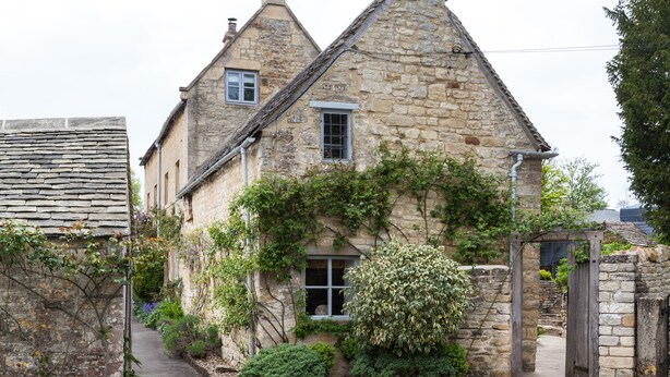 A stone building with a steeply pitched roof, a small window, and a wooden gate. - The Nook - Guiting Power, Cheltenham sleeping 6 guests (Guiting Power)