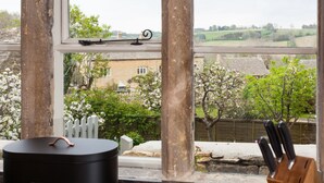 A view through a window with a rustic wooden frame, a black container, and a knife block. - The Nook - Guiting Power, Cheltenham sleeping 6 guests (Guiting Power)