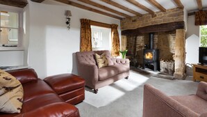 A cozy living room with a stone fireplace, leather sofas, and wooden beams. - The Nook - Guiting Power, Cheltenham sleeping 6 guests (Guiting Power)