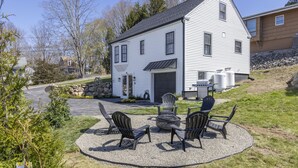 A two-story house with a garage, a patio with outdoor furniture, and a stone wall.