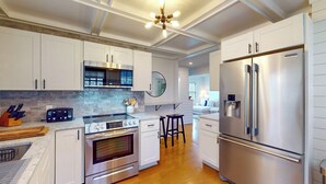 A modern kitchen with white cabinets, stainless steel appliances, a built-in oven, a microwave, and a refrigerator.