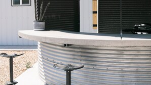 A cylindrical metal structure with a flat roof, a small window, and a door. - Barn  Stay (Hurricane)