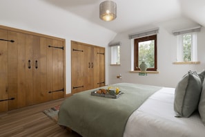 Une chambre à coucher avec un lit, une armoire en bois, une fenêtre donnant sur un paysage agréable et un panneau indiquant la sortie de secours en cas d’incendie.
