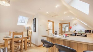 A modern kitchen with a wooden countertop, bar stools, and a skylight.