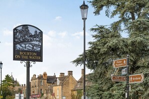 Señalización para 'Bourton on the Water' con indicaciones a 'Museo del Motor', 'Servicios', 'Información Turística' y 'Birdland'.