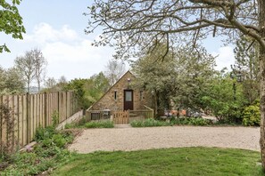 Une petite maison en pierre avec une allée en gravier et une clôture en bois.