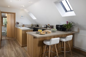 Une cuisine moderne dotée d’un îlot central, de tabourets de bar et d’une verrière.