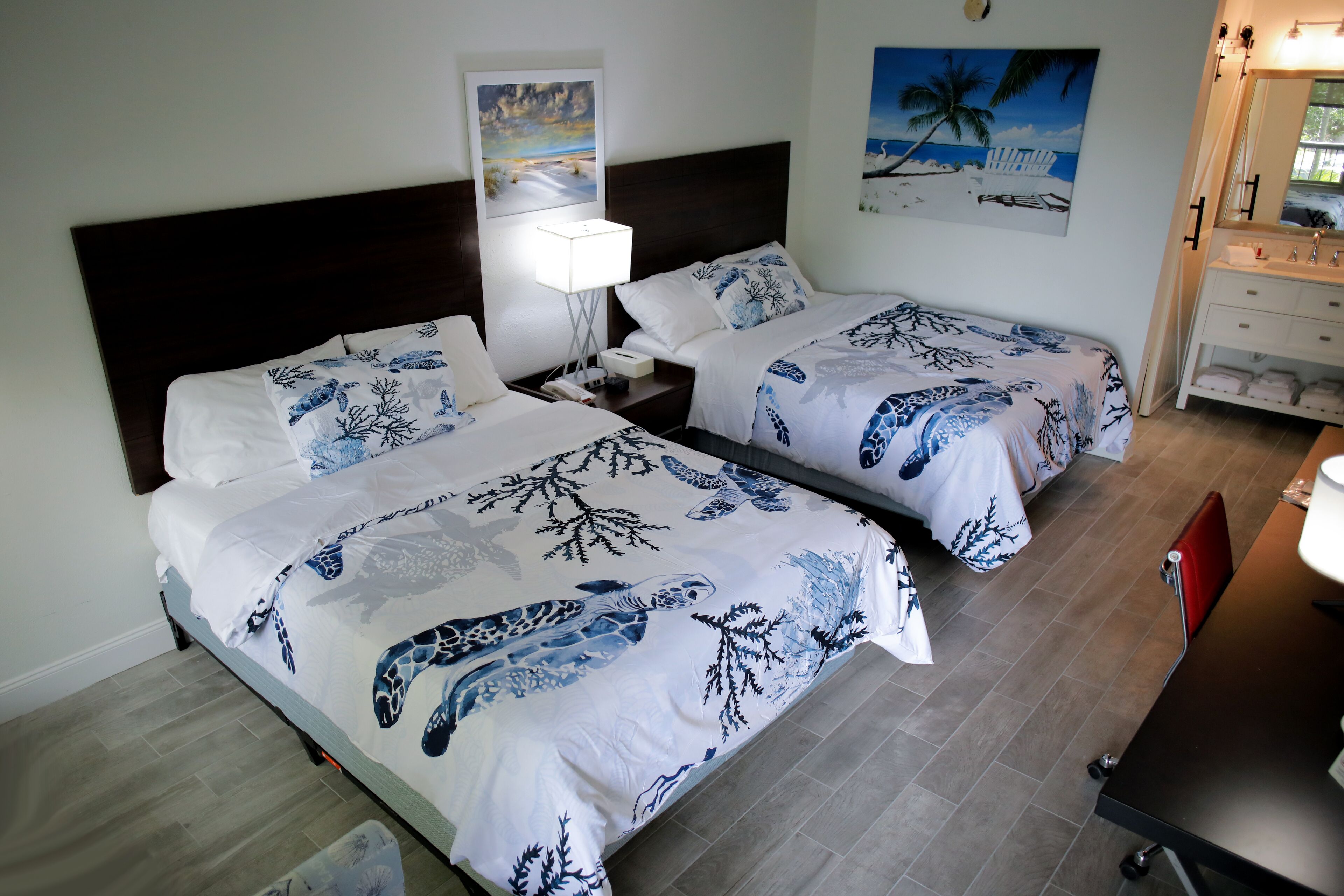 Een hotelkamer met twee bedden, een nachtkastje, een bureau en een badkamer.