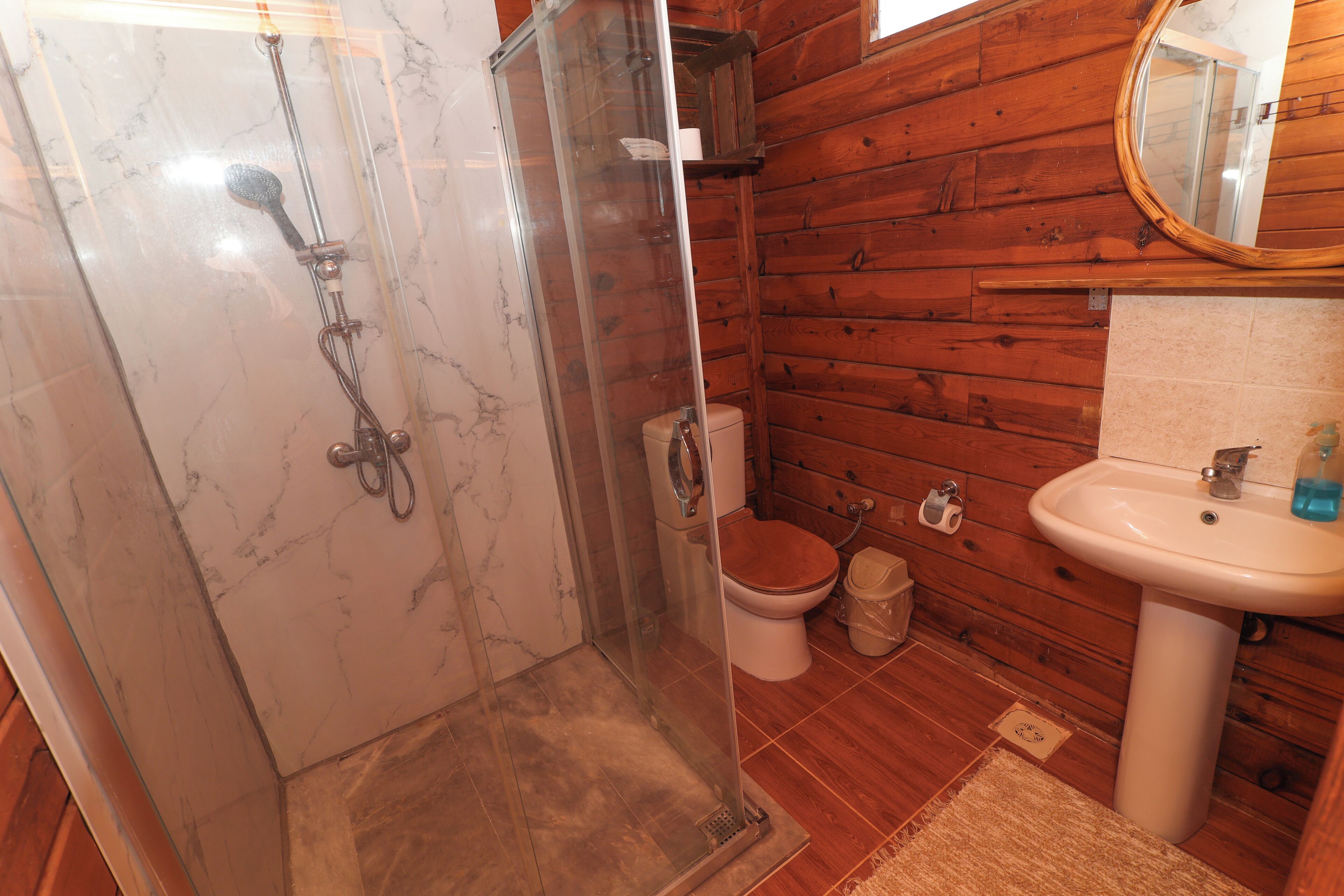 A bathroom with a glass-enclosed shower, a toilet, and a sink.