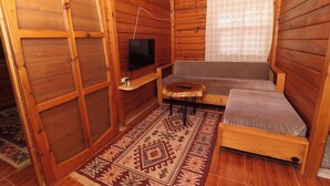 A wooden cabin interior with a sofa, a small table, a television, and a patterned rug. - Demre Sahildeki Ev Bungalov (Demre)