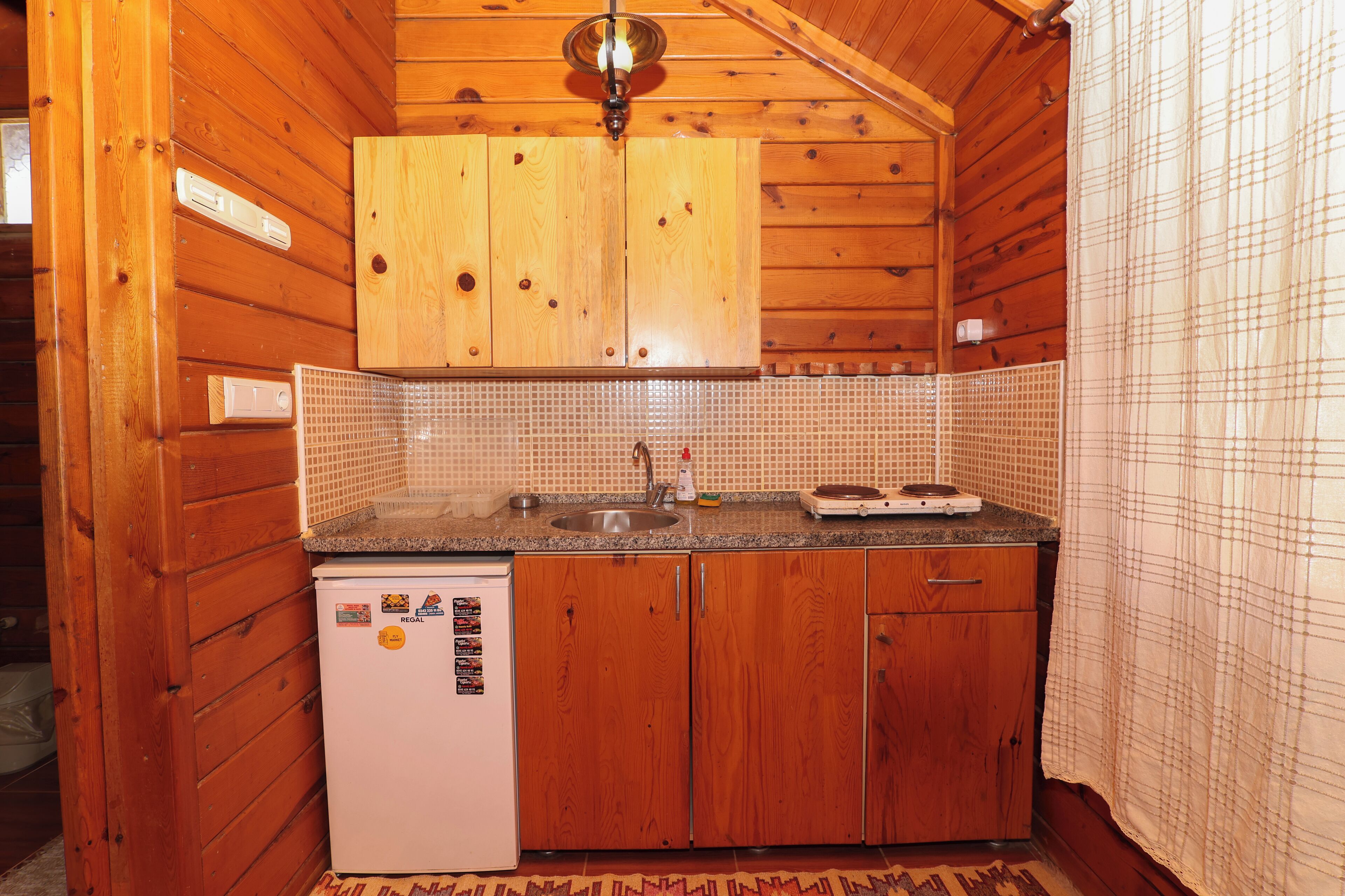 A compact kitchen with wooden cabinets, a built-in sink, a refrigerator, and a microwave.