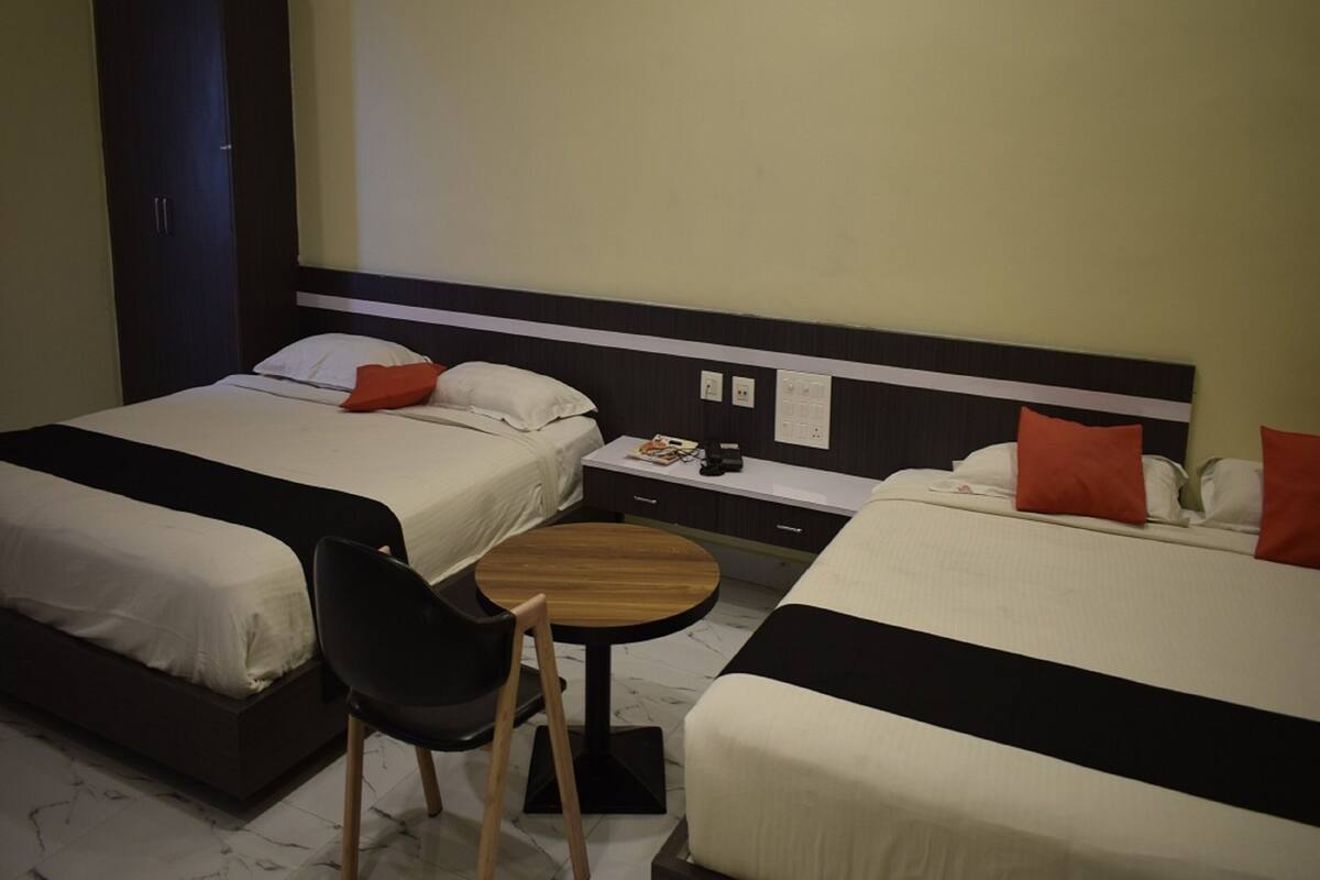 Ein Hotelzimmer mit zwei Betten, einem kleinen Tisch, einem Sessel und einem Schrank.