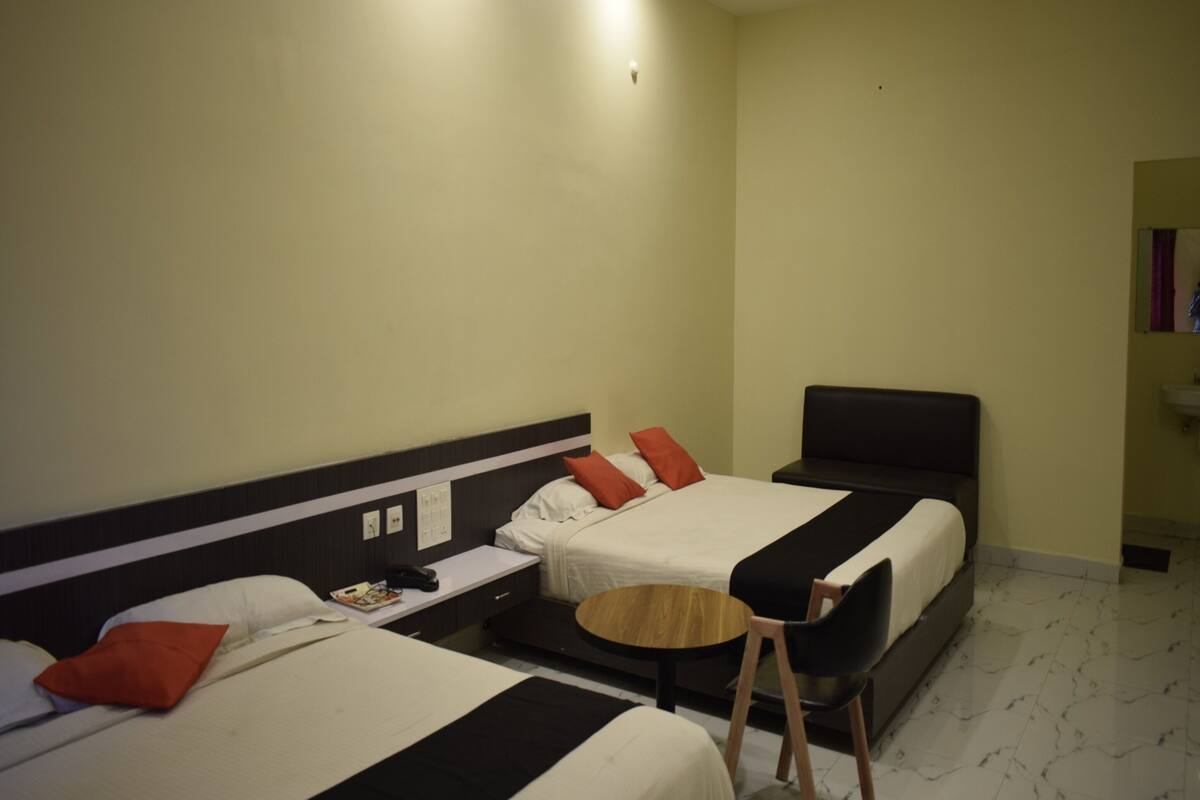 Ein Hotelzimmer mit zwei Betten, einem kleinen Tisch, einem Stuhl und einem Deckenventilator.