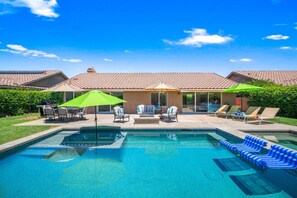 Um quintal com piscina, móveis de exterior e um espaço coberto de varanda.
