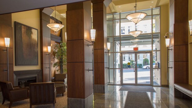 Un hall d’hôtel doté d’une cheminée, d’un espace salon et de grandes portes vitrées donnant sur l’extérieur.