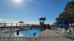 Un espace piscine avec des chaises longues, un gazebo et une vue sur l’océan.