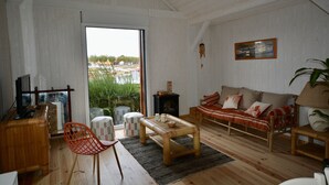 Ein geräumiges Wohnzimmer mit Holzboden, einer Couch, einem Couchtisch und einem Fernseher.