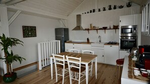Eine kleine Küche mit weißen Schränken, einem Holztisch und einem Blumentopf.