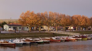 Ein Yachthafen mit verschiedenen Schiffen, einer Fußgängerbrücke und Bäumen in Herbstfarben im Hintergrund.