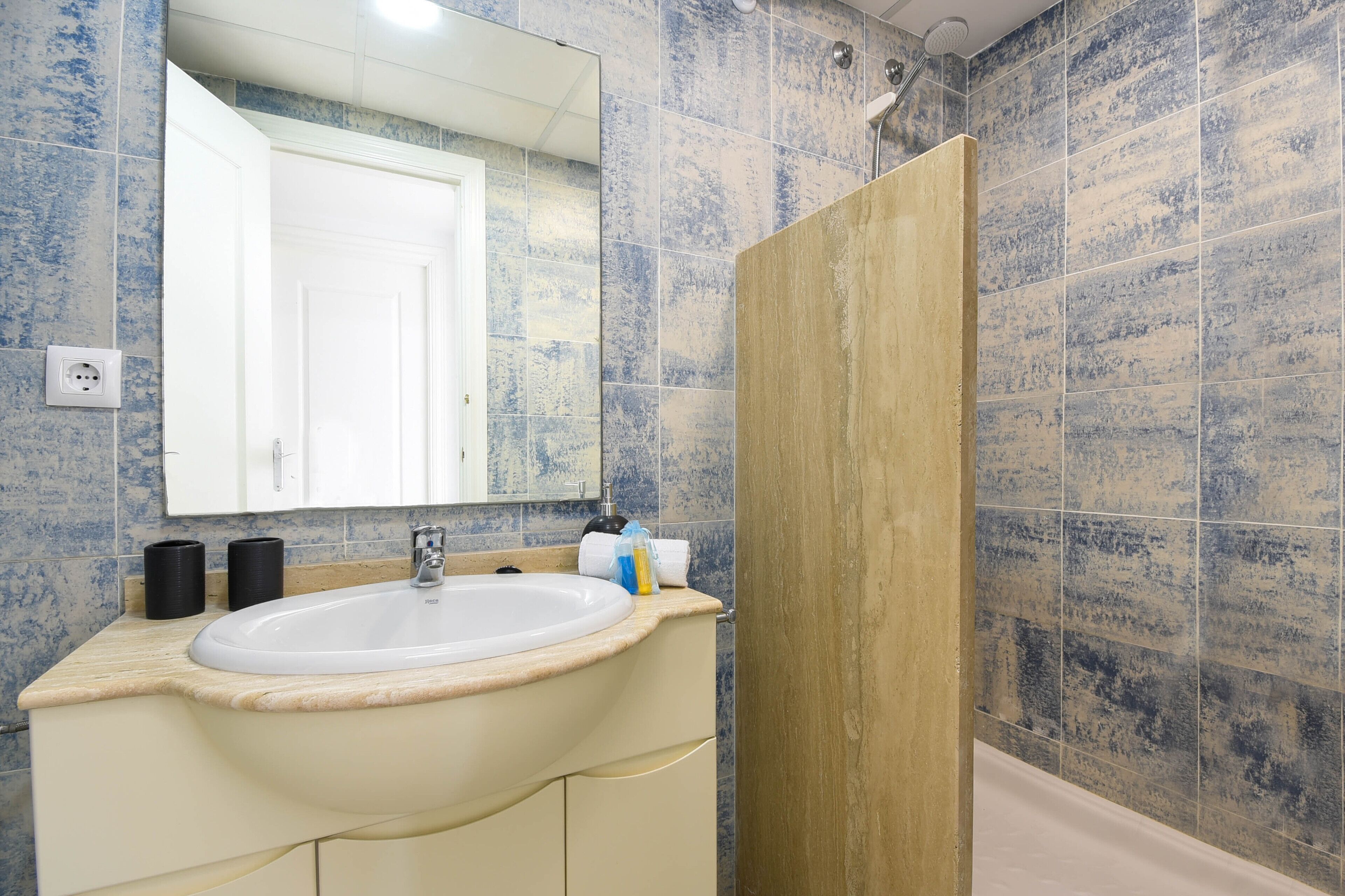 Une salle de bain avec un lavabo, un miroir et une douche.