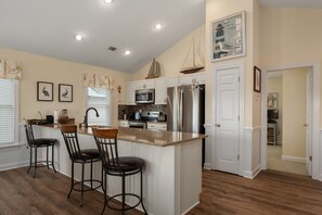 A kitchen with white cabinets, stainless steel appliances, and a central island with bar stools.