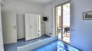 A room with a bed, a wardrobe, a television, and a sliding glass door leading to an outdoor area. - Casa Terry B: A graceful apartment located right on the beach, with Free WI-FI. (Castellabate)