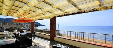 A terrace with outdoor seating and a view of the sea.