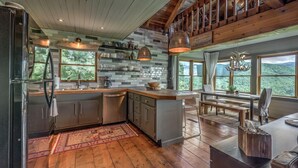 A modern kitchen with wooden cabinets, a built-in island, and large windows offering a view of the outdoors. - Top of the Ridge Chalet - Pet Friendly | Mountain Views | Hot Tub | Multiple Decks (Blue Ridge)
