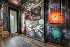 Un pasillo decorado con un mural de temática espacial, que muestra naves espaciales y cuerpos celestes.