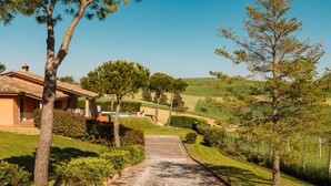 Uma propriedade rural com uma entrada de automóveis pavimentada que conduz a uma casa com telhado de cerâmica.