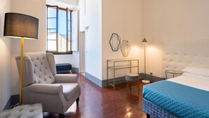 A hotel room with a bed, a chair, a lamp, a bedside table, and a wall-mounted geometric decoration. - Borgo Santa Croce in Firenze (Florence)