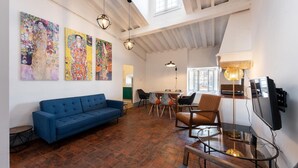 A spacious living area with a blue sofa, a dining table with chairs, and three large abstract paintings on the wall. - Borgo Santa Croce in Firenze (Florence)
