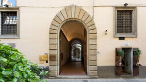 An entrance with an arched doorway, a sign reading "AQUA FLOR," and a potted plant on the right. - Borgo Santa Croce in Firenze (Florence)