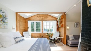 A bedroom with a large bed, two chairs, a sofa, and a window with a view of trees. - Sunset Garden Retreat-Sea & Mountain View w/ Sauna (Bremerton)