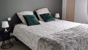 Une chambre à coucher comprenant un lit, deux tables de chevet, une lampe et un panneau décoratif mural.