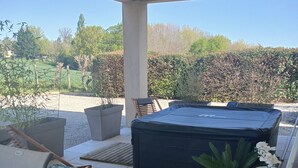 Un patio couvert comprenant un jacuzzi, des sièges et des plantes en pot.
