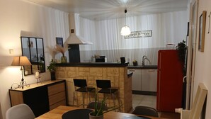 Une cuisine compacte dotée d’un îlot central, d’une table à manger avec des sets de table noirs et d’un réfrigérateur rouge.