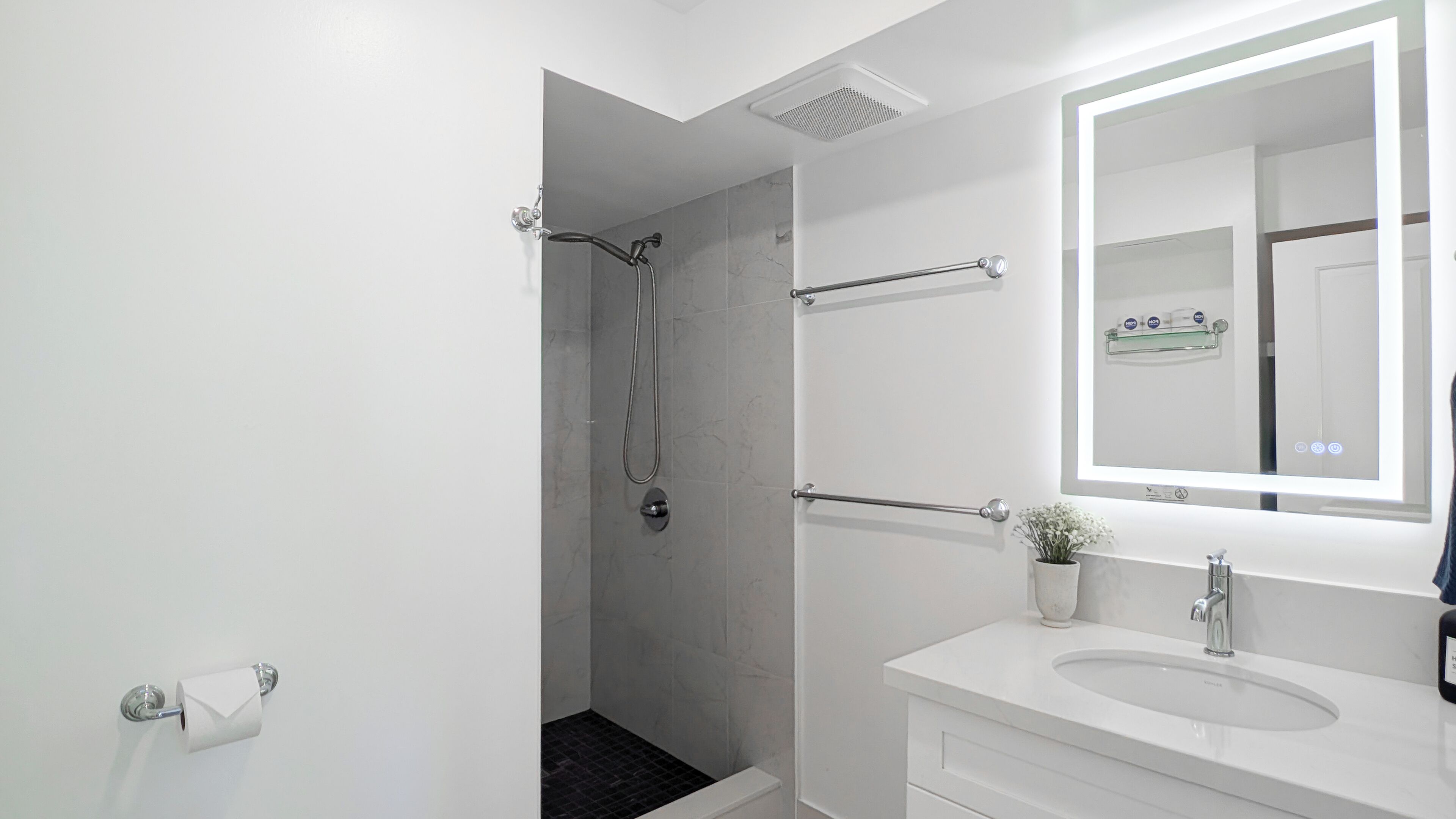 Ein modernes Badezimmer mit Dusche, Toilette, Waschbecken und Spiegel.