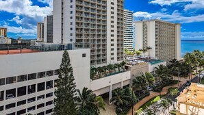 A high-rise hotel with multiple balconies, a rooftop pool area, and a view of the ocean. - High Floor 2BR/2BA+Den 5beds Partial Ocean View + 1 Parking 1 min from the beach (Honolulu)