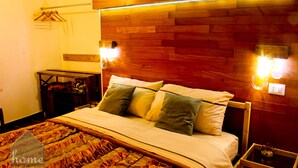 Een keurig opgemaakt bed met een houten hoofdbord, twee nachtkastjes met lampen, en een wandlamp.
