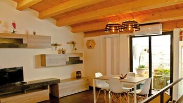 Una cucina moderna con zona pranzo, travi in legno a soffitto e un'ampia finestra con piante in vaso.