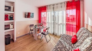 Een moderne woonkamer met een bank, een eettafel met stoelen en een aan de muur bevestigde televisie.