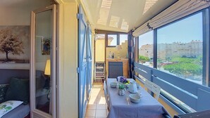 Un balcón con una mesa lista para comer, una silla y vistas a edificios y vegetación.