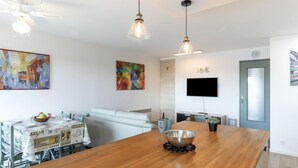 Une cuisine moderne avec un îlot central en bois, une table à manger et un téléviseur fixé au mur.